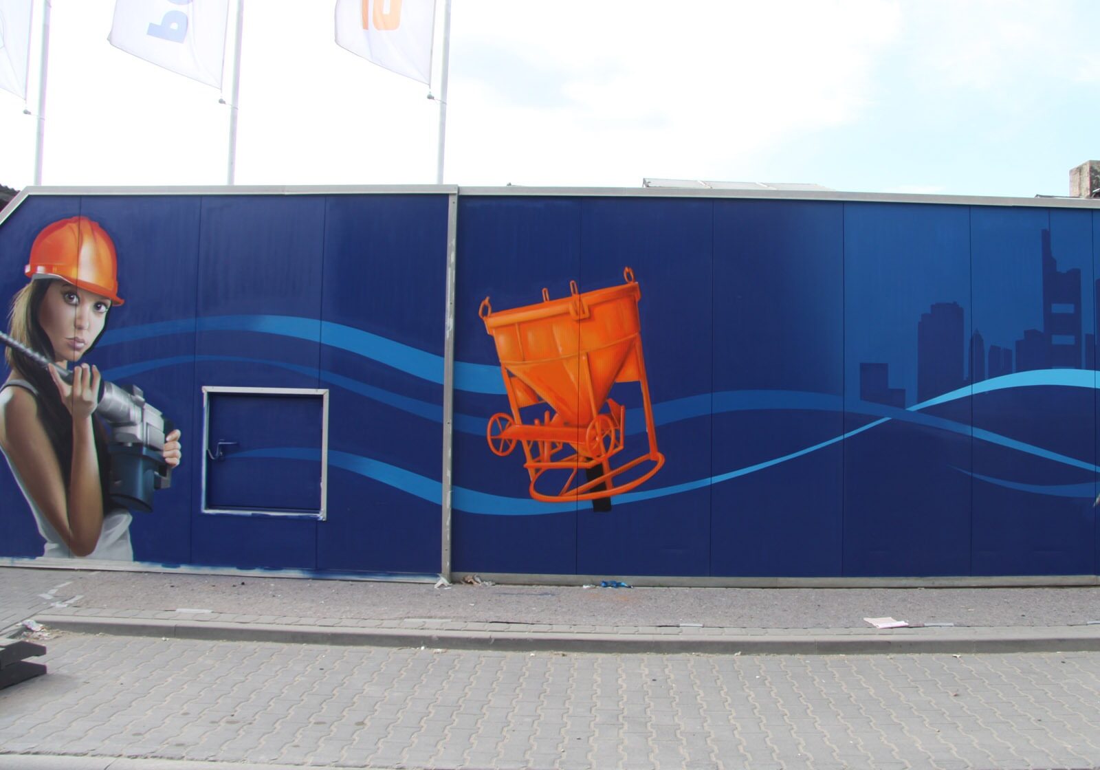 graffitikuenstler-graffitiauftrag-artmos4-rhein-main-baumaschinen-2013-bohrer-menschen-fotorealistisch-blau-orange-aussen