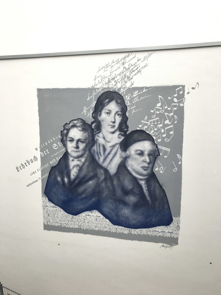 graffitiauftrag-graffitikuenstler-artmos4-baugenossenschaft-odenwaldring-menschen-raster-schrift-offenbach-musik-folie-raster-aussen-blau-weiss