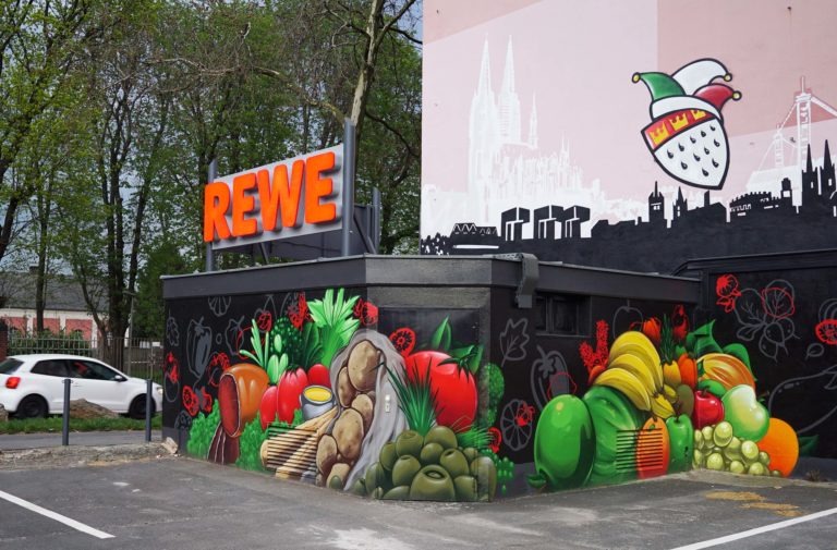 graffitiauftrag-graffitikuenstler-artmos4-rewe-skyline-obst-gesicht-schrift-wappen-aussen-schwarz-bunt-fotorealistisch-illustrativ-handel