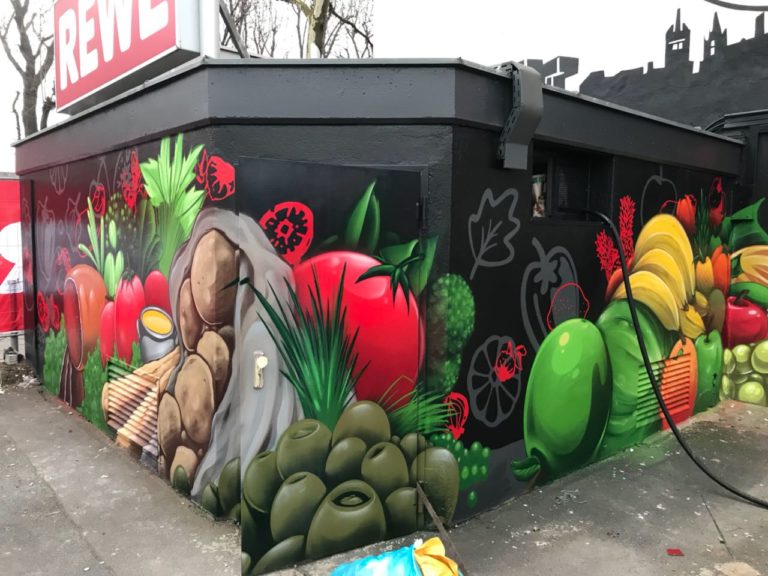 graffitiauftrag-graffitikuenstler-artmos4-rewe-skyline-obst-gesicht-schrift-wappen-aussen-schwarz-bunt-fotorealistisch-illustrativ-handel