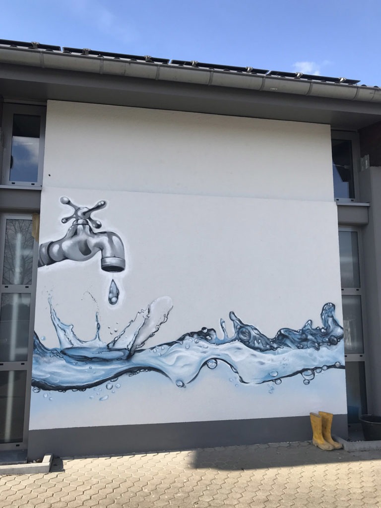 graffitiauftrag-graffitikuenstler-artmos4-stadtwerke-floersheim-wasser-tropfen-logo-wasserhahn-welle-aussen-blau-fotorealistisch
