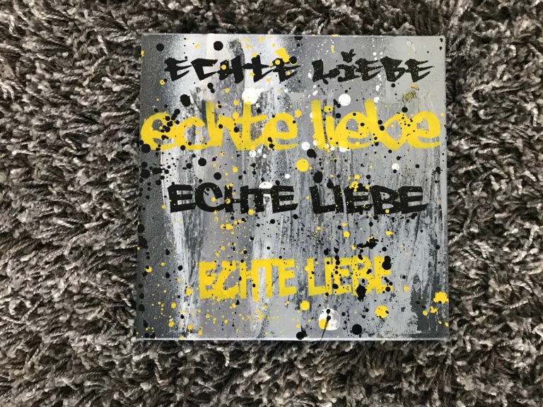 graffitiauftrag-graffitikuenstler-artmos4-zuhause-im-glueck-bvb-leinwand-gelb-schwarz-grau-echte-liebe-slogan-trashig